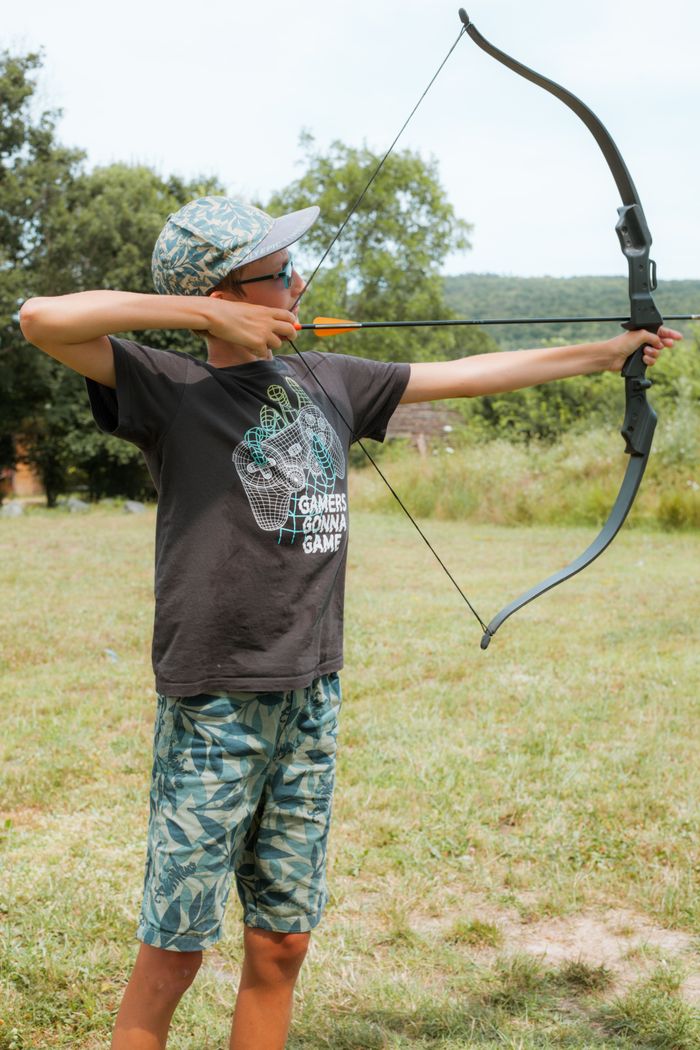 Mastering the First Impression: Your intriguing post title goes here Teenager practicing archery in a sunny outdoor setting, aiming a bow.