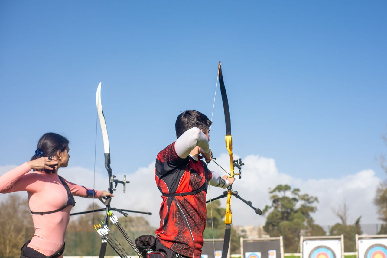 services-02 Two archers take aim at targets during a sunny day outdoors in Portugal.